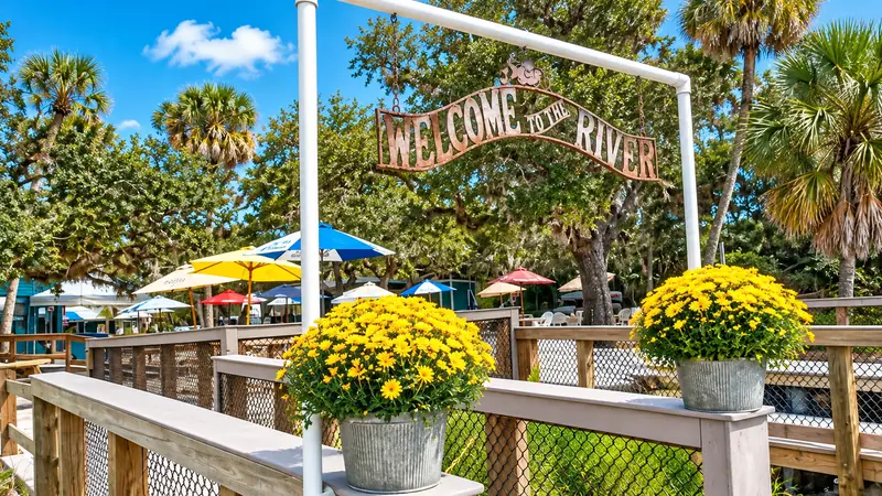 Welcoming riverside entrance decorated with flowers and shaded seating