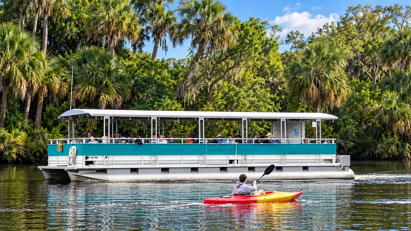 River tour boat traveling alongside a colorful kayak