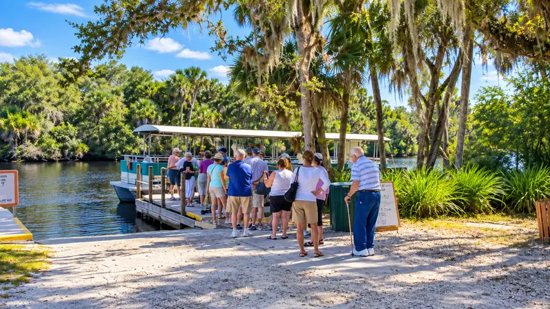 Visitors gathered at a shaded waterside walkway and dock