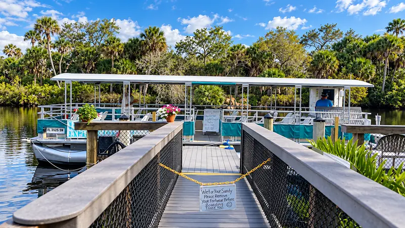 Wooden walkway leading toward a covered boat on the river