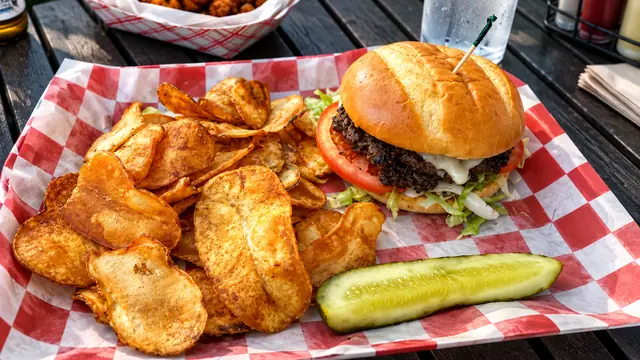 Burger served with golden potato chips and pickle