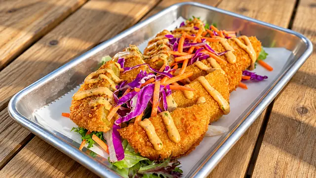 Crispy croquettes with colorful slaw on a metal tray